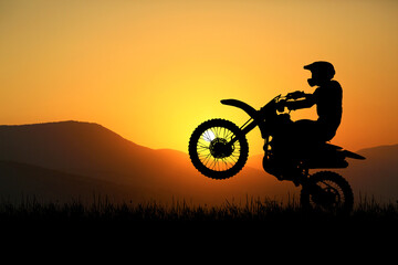 Fototapeta na wymiar Silhouette of a motocross motorcycle lifting the front wheel. Adventure and Action Concepts