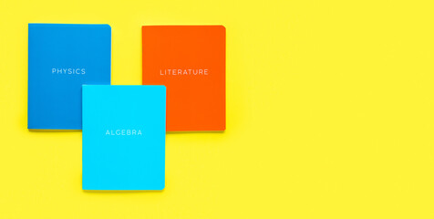 Multicolored exercise books on yellow background, close up. Education and reading concept - group...