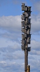 A huge number of wooden birdhouses are fixed on a wooden pole. A bright sunny day. Skyscraper concept for birds.