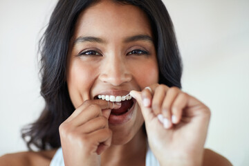 Making the health of my teeth a priority. Portrait of an attractive and happy young woman flossing her teeth.