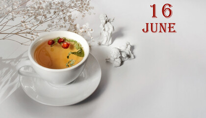 calendar date on light background with a porcelain cup of green tea, white gypsophila and angels with copy space. June 16 is the sixteenth day of the month