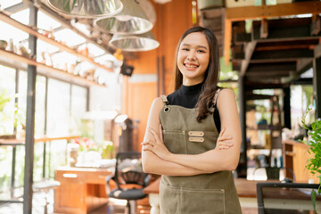 Obraz na płótnie Canvas portrait of asian adult female woman wear apron standing at entrance of her workshop pottery studio incasual cloth relax smiling confident and warm welcome,asian woman with her home studio workshop