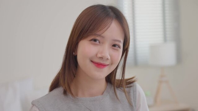 Slow motion portrait happy Asian teenager woman having beautiful smile looking at camera. Attractive cheerful asian woman lifestyle at home concept