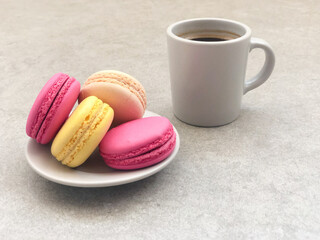 olorful delicious macaroons and cup of coffee on gray table