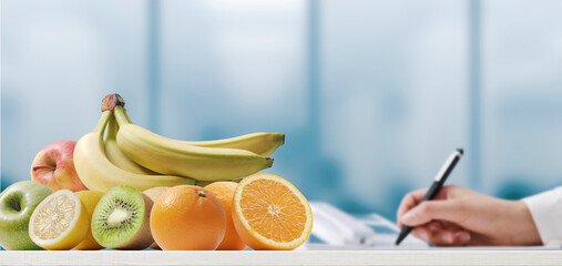 Nutritionist writing a diet plan and healthy fruits