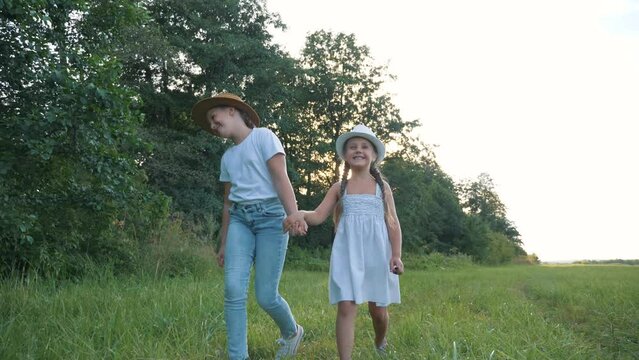 kids toddler dream of walking together in park at sunset. happy kids park concept. two sisters are playing in green park summer for walk. Children are having fun on summer day walking on green grass.