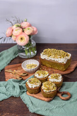 Pistazienkuchen und Cupcakes mit Frosting, Kaffeetisch Frühling mit Kuchen und Blumenstrauß