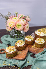 Pistazienkuchen und Cupcakes mit Frosting, Kaffeetisch Frühling mit Kuchen und Blumenstrauß