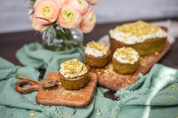 Pistazienkuchen und Cupcakes mit Frosting, Kaffeetisch Frühling mit Kuchen und Blumenstrauß