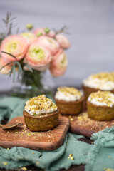 Pistazienkuchen und Cupcakes mit Frosting, Kaffeetisch Frühling mit Kuchen und Blumenstrauß