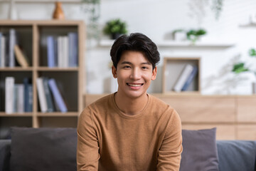 Asian handsome man looking at camera smile at home.Happy young smart businessman smile and...