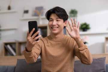 Asian handsome man meeting with business team via video conference call at Home.Hand up Greetings with family group in online video call.Positive young business man speaking with friends in video call © 220 Selfmade studio