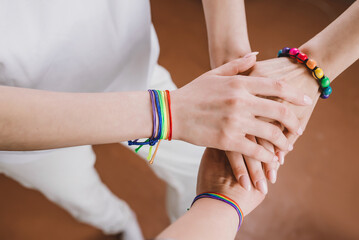 LGBT pride celebration. Hands of a group of three people with LGBT flag bracelets