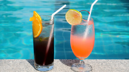 Fresh summer tropical cocktails drinks near swimming pool in modern luxury resort. Vacation, travel, holidays in Thailand. Drink a cocktail on vacation on edge of the blue pool. Poolside party