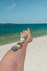 colorful rocks on woman hand at sea summer beach