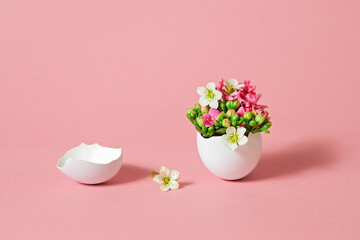 White Easter egg with beautiful spring flowers on pink background.