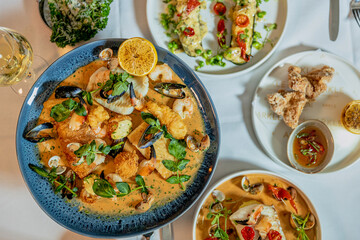 Assorted view of dinner table with delicious food set  for two, seafood,Salmon with broccoli, salad, club sandwich, salad with quinoa, tartar from beef