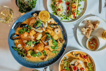 Assorted view of dinner table with delicious food set  for two, seafood,Salmon with broccoli, salad, club sandwich, salad with quinoa, tartar from beef