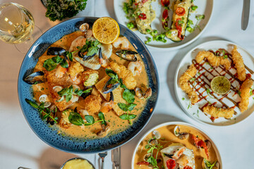 Assorted view of dinner table with delicious food set  for two, seafood,Salmon with broccoli, salad, club sandwich, salad with quinoa, tartar from beef