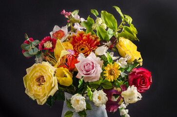 Elegant bouquet of flowers in a vase on a black background in dark style, still life