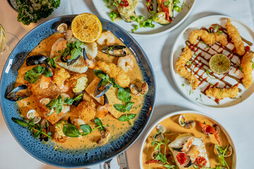 Assorted view of dinner table with delicious food set  for two, seafood,Salmon with broccoli, salad, club sandwich, salad with quinoa, tartar from beef