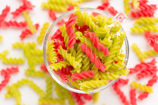 Close-up background of Fusille and Rotini in a glass bowl on white. pasta colorata
