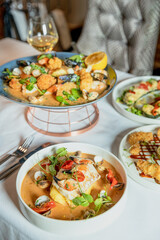 Assorted view of dinner table with delicious food set  for two, seafood,Salmon with broccoli, salad, club sandwich, salad with quinoa, tartar from beef