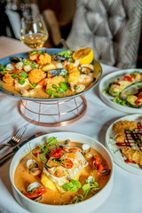 Assorted view of dinner table with delicious food set  for two, seafood,Salmon with broccoli, salad, club sandwich, salad with quinoa, tartar from beef