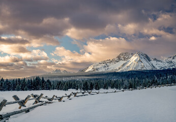 Pole fence leads to the distant Sawtooth winter mountain range in Idaho