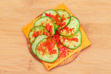 Fototapeta na wymiar Crispy Cracker Sandwich with Fresh Cucumber, Cheese and Paprika on Cutting Board. Diet Food. Easy Breakfast. Quick and Healthy Sandwiches. Crispbread with Tasty Filling. Healthy Dietary Snack