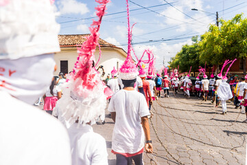 Group of unrecognizable young people seen from behind carrying chains and dressed in traditional...