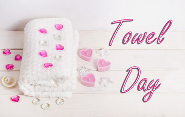 Fototapeta na wymiar Towel day lettering, white towel with pink hearts on a white wooden background