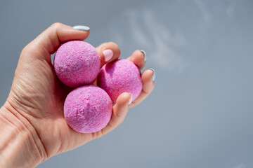 salt pink bath bombs lie on a woman's hand