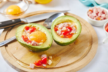 Avocado with egg, ham, tomatoes and cheese. Keto lunch recipe. Before baking