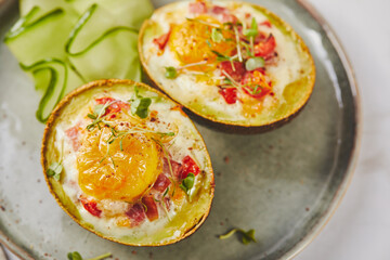 Avocado baked with egg, ham, tomatoes and cheese. Keto lunch recipe. After baking