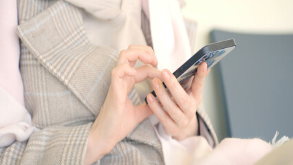 Woman is sitting and looking at phone. Action. Close-up of beautiful woman sitting on phone. Woman smiling is sitting on phone on clear sunny day