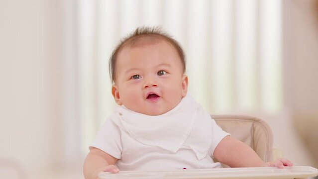 Happy asian newborn baby sit on baby chair smile and laughing with parent or family at home.Adorable baby boy cheerful enjoy with good moment in warmth place.growth with good Emotional Quotient