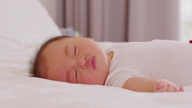 Happy asian newborn baby lying sleeps on a white bed comfortable and safety.Cute Asian newborn sleeping and napping at warmth place deep sleep and fresh breathing.Newborn Baby Sleep concept