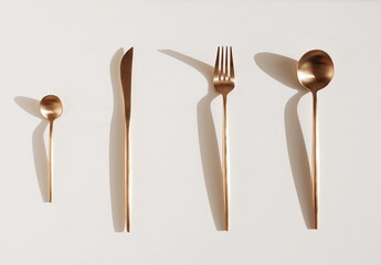 Metal cutlery set and sunlight shadow composition top view on white background. Food concept. Poster