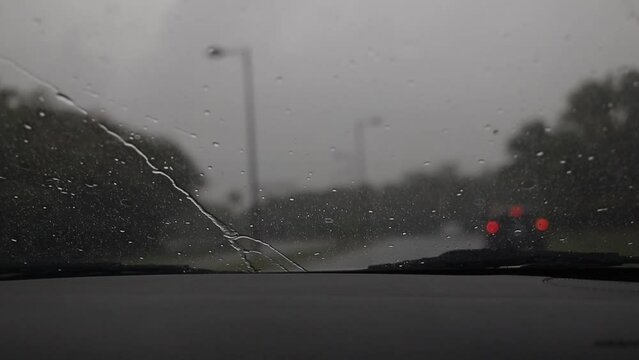 auto en movimiento en autopista con lluvia, plano amplio con fondo borroso, parabrisas encendido en lluvia
