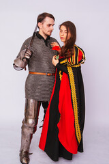 Knight in armor with a sword and a young woman in a medieval black dress. Love story. Married...