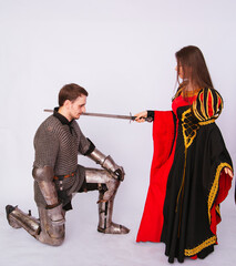 Knight in armor with a sword and a young woman in a medieval black dress. Love story. Married...