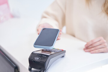 Beauty clinic client making contactless payment at reception desk