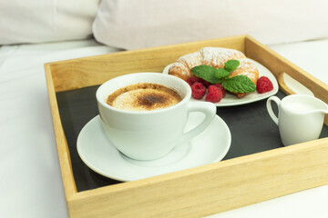 Coffee, orange juice and a croissant on a wooden stalk