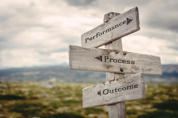 performance process outcome text quote written in wooden signpost outdoors in nature. Moody theme feeling. - 499468511
