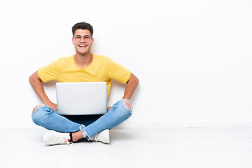Young man sitting on the floor isolated on white background posing with arms at hip and smiling