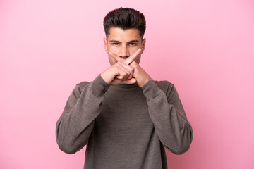 Obraz premium Young caucasian man isolated on pink background showing a sign of silence gesture