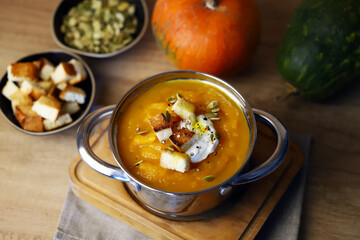 Pumpkin soup in a saucepan with croutons.