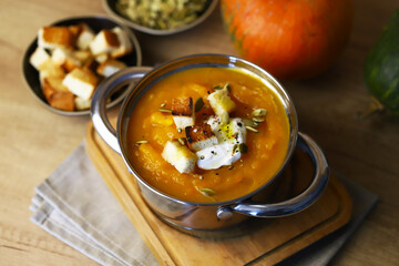 Pumpkin soup in a saucepan with croutons.