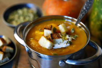 Pumpkin soup in a saucepan with croutons.